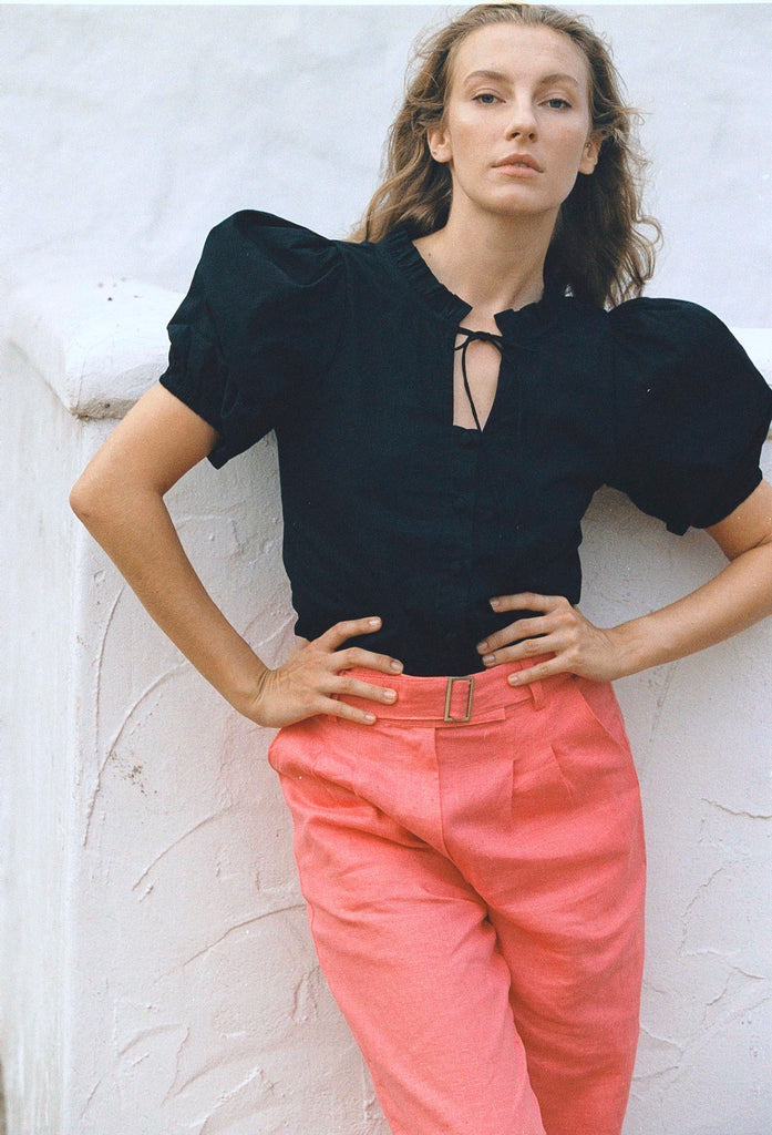 Black cotton puff-sleeve blouse with buttons paired with salmon colored pants