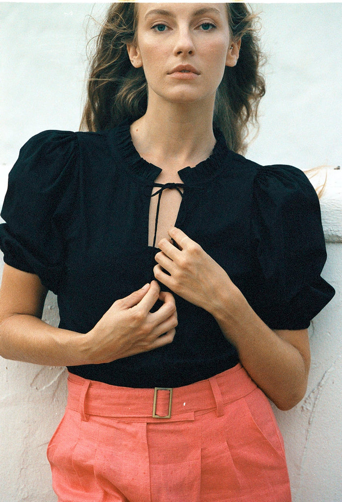 Black cotton puff-sleeve blouse with buttons paired with salmon colored pants